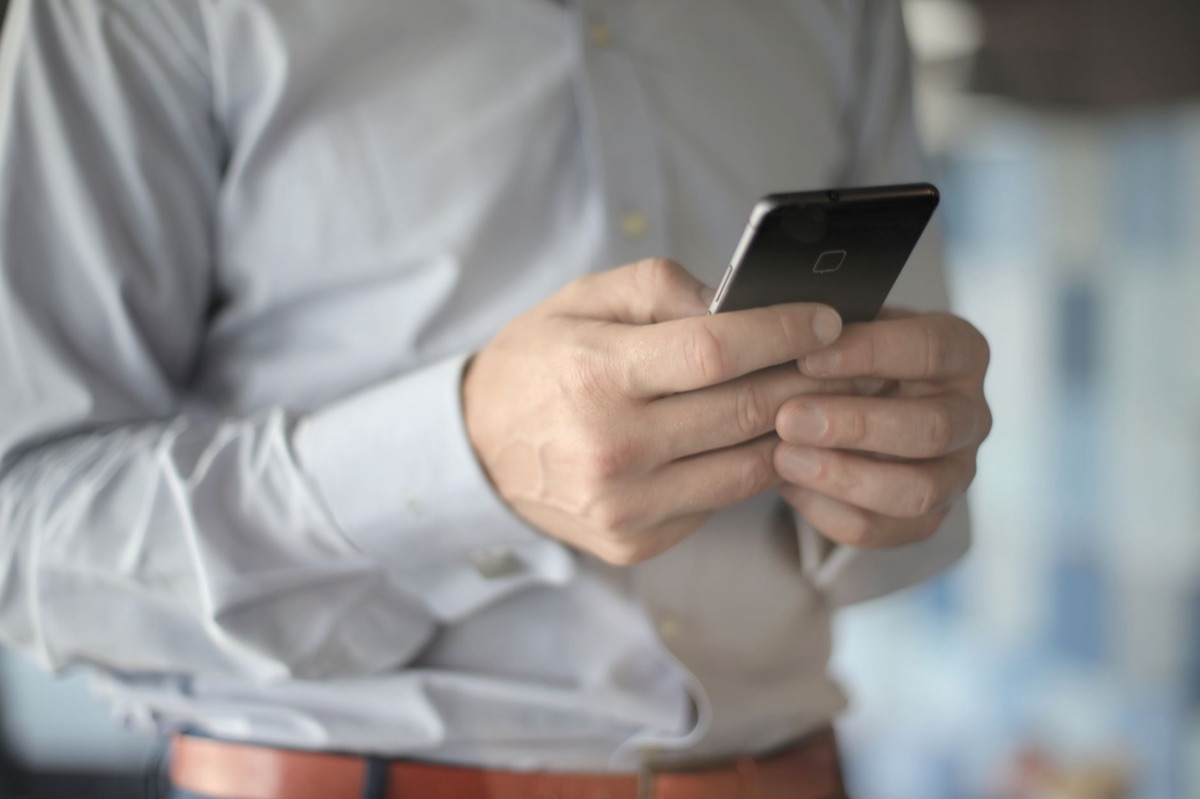 Entrepreneur utilisant un CRM sur smartphone avec des données clients et un tableau de bord de ventes