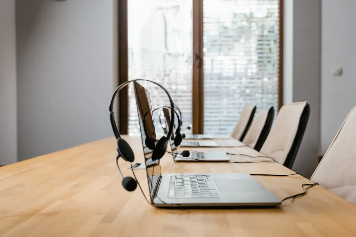 Modern conference room with laptops and headsets lined up ready for a meeting.